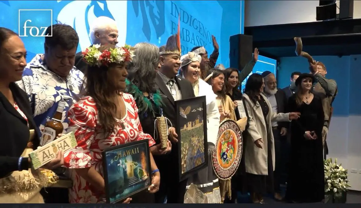 A group holding framed artwork and gifts together on a stage