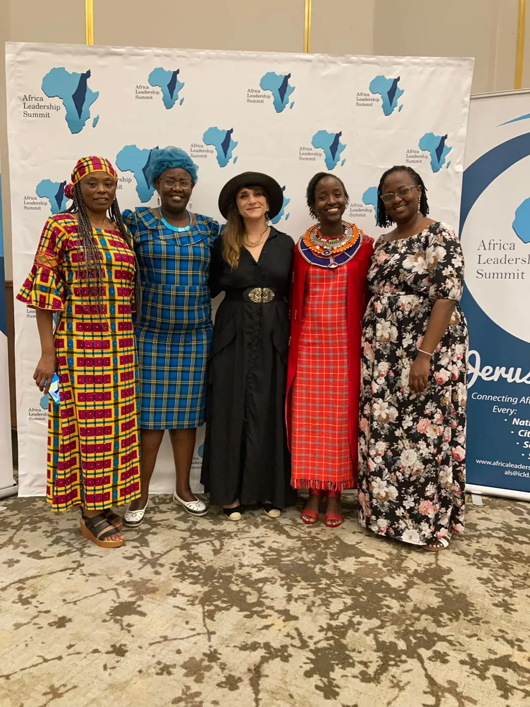 Five women posing in front of an Africa Leadership Summit backdrop