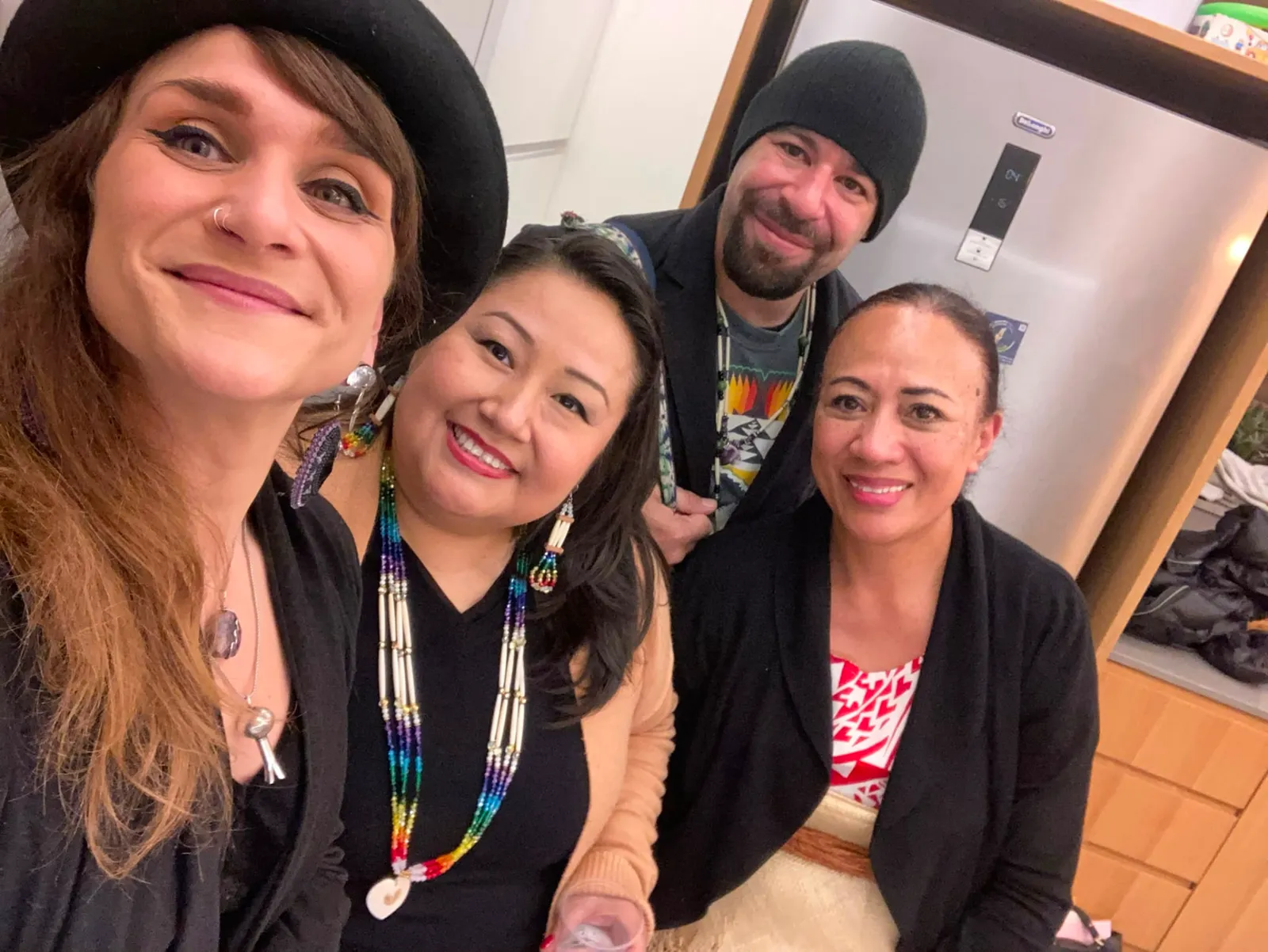 Four people smiling for a selfie indoors