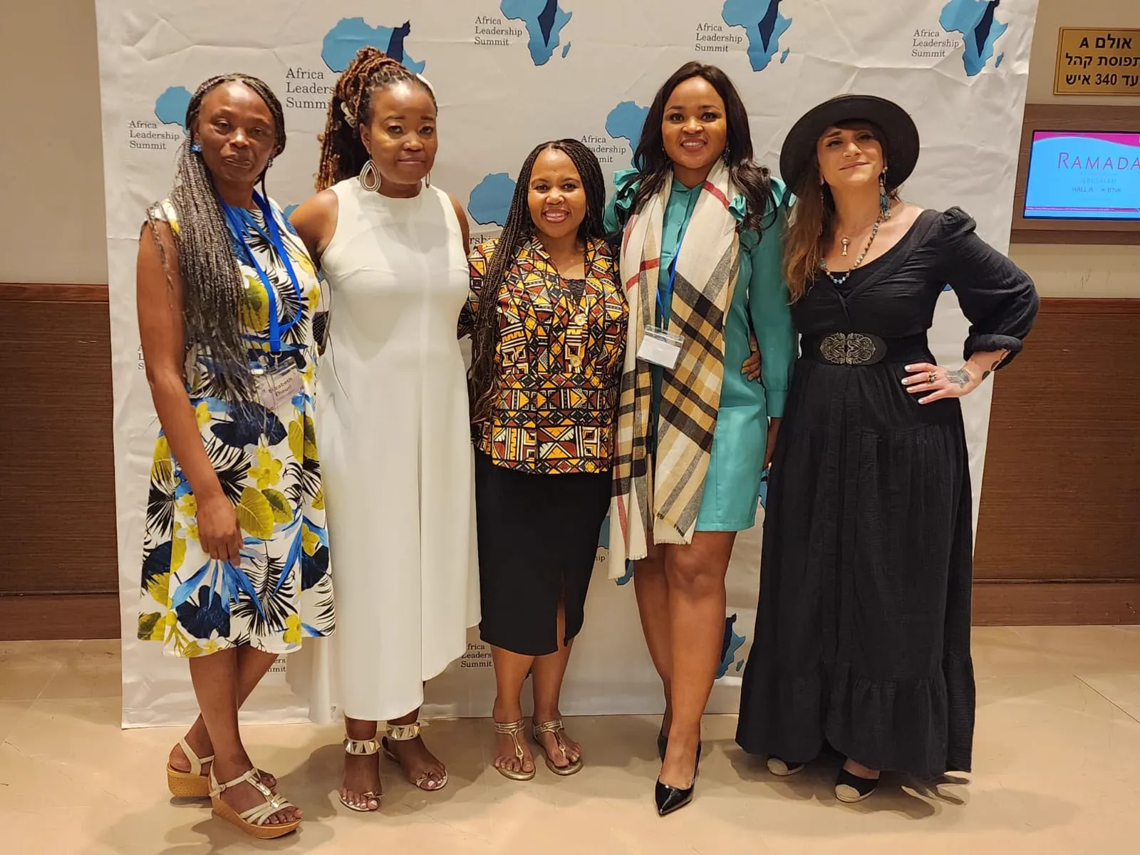 Five women posing in front of an Africa Leadership Summit backdrop