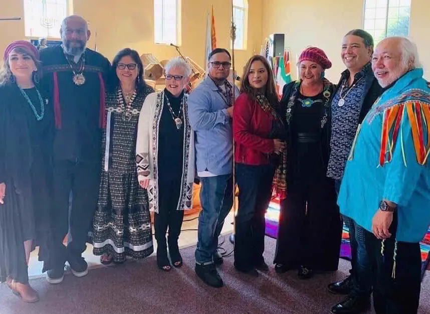 A group of people in traditional and contemporary clothing standing together indoors