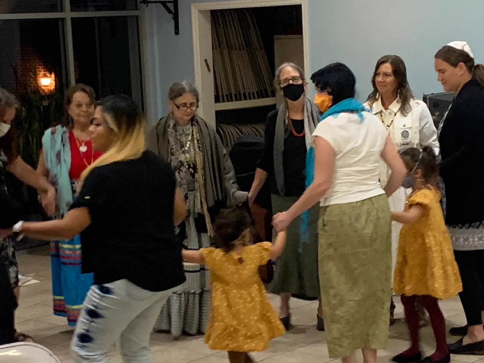 People holding hands and dancing in a circle indoors
